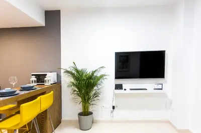 a living room with a television and a table with yellow chairs at Total Valencia Old City Luxury in Valencia