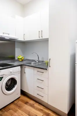 a white kitchen with a sink and a washing machine at Down Town in Valencia