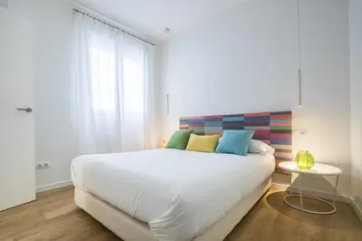 a bedroom with a large white bed with colorful pillows at Valencia Luxury - Boutique Redonda in Valencia