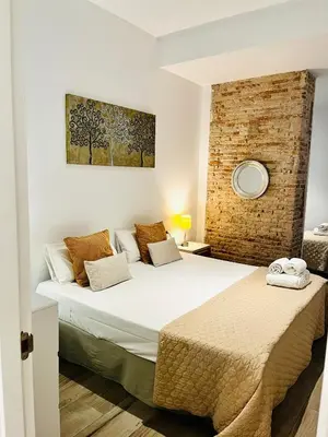 a bedroom with two beds and a brick wall at Travel Habitat Ayuntamiento in Valencia
