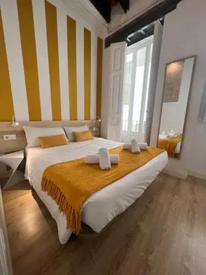 a bedroom with a large bed with yellow and white stripes at Baron Suites Reina in Valencia
