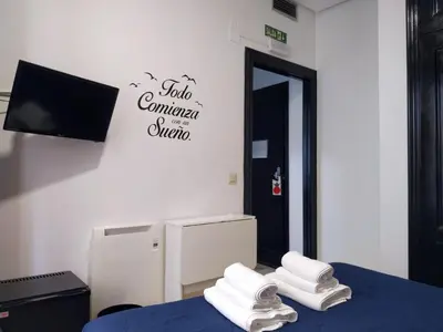 a room with a bed and a tv and towels at Flats Friends Plaza de la Reina in Valencia