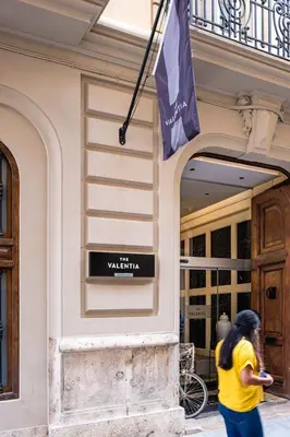 a woman walking in front of a building with a flag at The Valentia Cabillers in Valencia