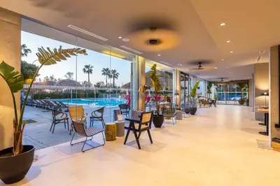 a lobby with chairs and tables and a pool at Hotel Barú in Sagunto