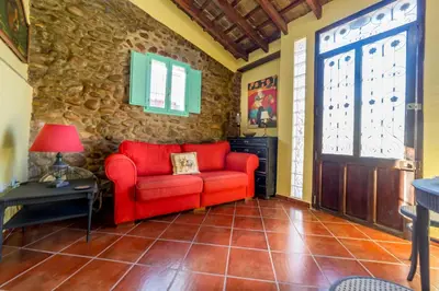 a living room with a red couch and a stone wall at Villa Lupita in Alquerías del Niño Perdido