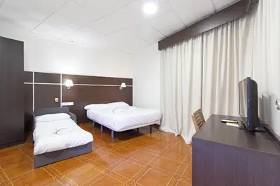 a hospital room with two beds and a television at Hotel Sagunto in Sagunto