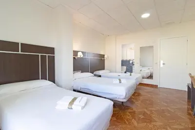 a hotel room with three beds and a bathroom at Hotel Sagunto in Sagunto