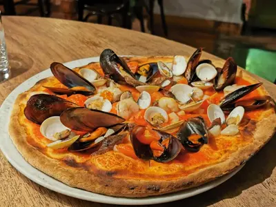 a pizza with mussels and seafood on a plate on a table at Hotel L'Escala in Cullera