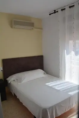a bedroom with a white bed with a window at Hotel L'Escala in Cullera