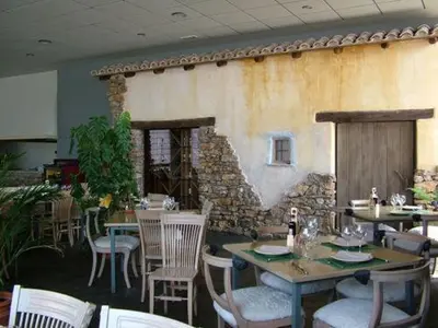 a restaurant with tables and chairs and a stone wall at Hotel Puerta de la Serrania in Lliria