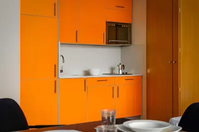 a kitchen with orange cabinets and a table at Aparthotel Wellness in Paterna