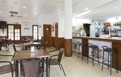 a restaurant with tables and chairs and a bar at Hotel Olympia Ronda I in El Puig