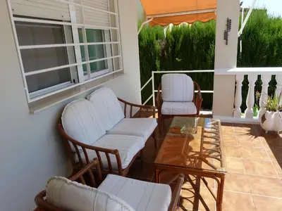 a porch with white chairs and a glass table at Adosado Calle Mar Cantabrico in Puebla de Vallbona