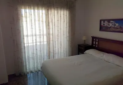 a bedroom with a bed and a window with curtains at Apartamentos Milenio in Cullera