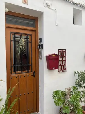 a wooden door on a white building with plants at Apartamentos turísticos 