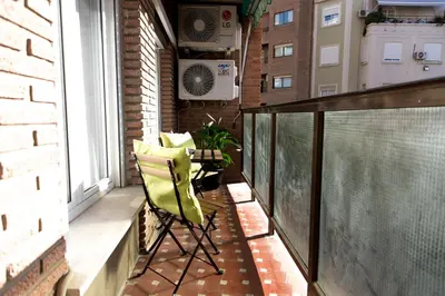 a balcony with a green chair and a window at MD Vila Barbera in Valencia