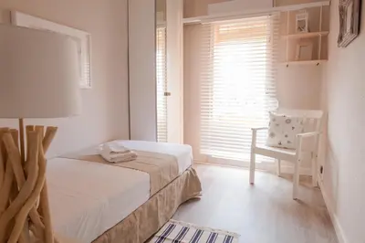 a bedroom with a bed and a chair and a window at MD Benlliure Cabañal Beach in Valencia