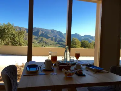 a wooden table with wine glasses and a view of mountains at Mar de Fulles in Alfondeguilla