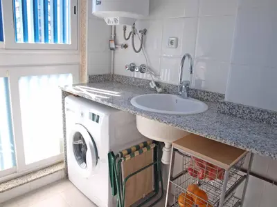 a bathroom with a sink and a washing machine at ApartUP Patacona Panoramic in Valencia