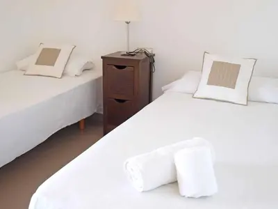 two beds in a room with white sheets and a night stand at ApartUP Patacona Panoramic in Valencia