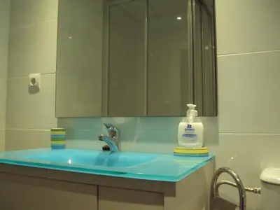 a bathroom with a blue sink and a mirror at Mirant el Mar in Port Saplaya