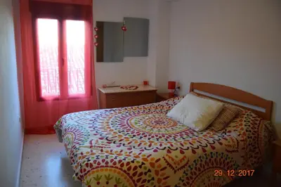 a bedroom with a bed and a red door at La Vista al mar de Belén in Port Saplaya
