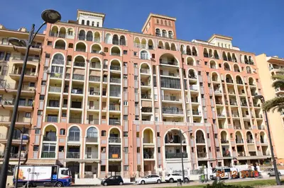 a large building with cars parked in front of it at La Vista al mar de Belén in Port Saplaya