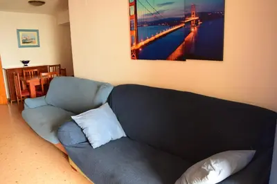 a couch in a living room with a picture of a bridge at La Vista al mar de Belén in Port Saplaya