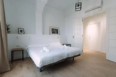 a white bedroom with a white bed and a door at Concept Rooms in Valencia