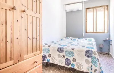a bedroom with a bed and a wooden cabinet at Nice Home In Alberique in Alberique