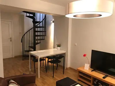 a living room with a table and a staircase at Atico En El Centro in Valencia