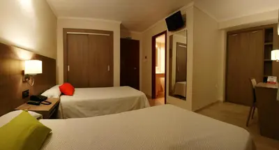 a hotel room with two beds and a television at Hotel Avenida Plaza in Alzira