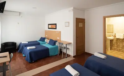 a hotel room with three beds and a sink at Hostal Mitre Paterna in Paterna