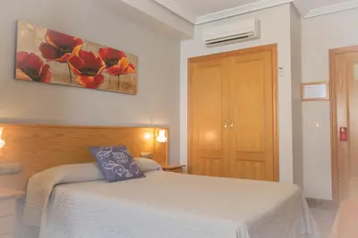a bedroom with a bed and a painting on the wall at L'Oncle Pere Habitacions in L'Alcúdia