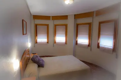 a bedroom with a bed in a room with windows at L'Oncle Pere Habitacions in L'Alcúdia