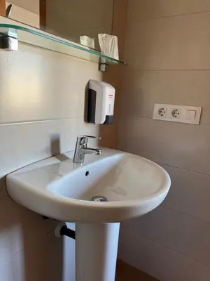 a bathroom sink with a soap dispenser on the wall at L'Oncle Pere Habitacions in L'Alcúdia