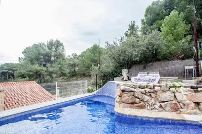a swimming pool with a rock retaining wall and a swimming pool at Ca Carmela casa con Encanto con Piscina 
