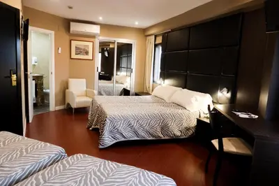 a hotel room with two beds and a desk at Hotel Benetusser in Benetúser