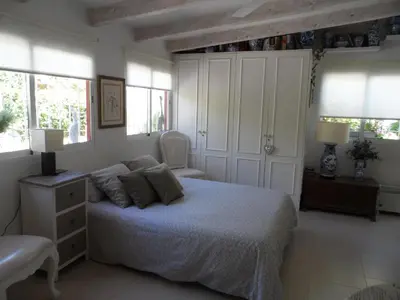a bedroom with a bed and a chair and windows at Casa con jardín frente Playa de Burriana in Burriana