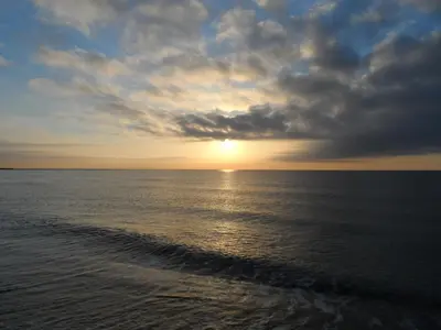 a sunset over the ocean with a trail in the water at Casa con jardín frente Playa de Burriana in Burriana
