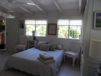 a bedroom with a bed and two chairs and windows at Casa con jardín frente Playa de Burriana in Burriana
