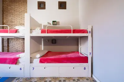 a room with two bunk beds with red sheets at Purple Nest Hostel in Valencia