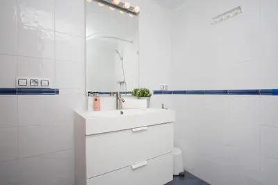 a white bathroom with a sink and a mirror at Apartments Cullera Beach in Cullera