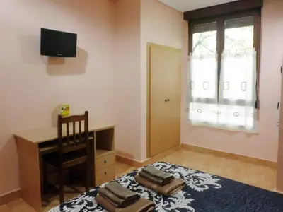 a bedroom with a bed with a desk and a window at Hostal Abastos in Valencia