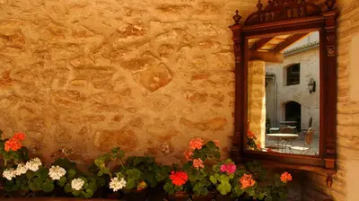 a mirror on the side of a stone wall with flowers at La Mozaira in Alboraya