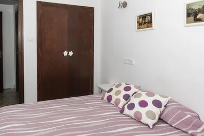 a bedroom with a bed with purple sheets and a cabinet at Europa B 6º-23 in Cullera