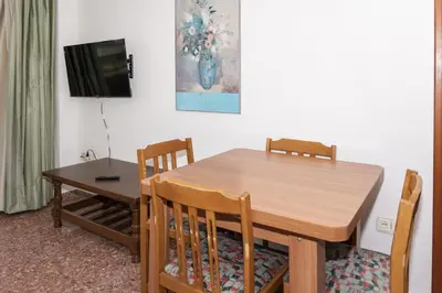 a dining room with a wooden table and a television at Florazar 2, Vi-1-B in Cullera