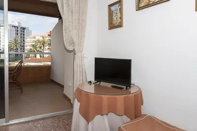 a television on a table in a room with a balcony at Florazar 2, Vii-2-A in Faro de Cullera