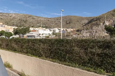 a wall with bushes and buildings and mountains in the background at Florazar 2, Vii-2-A in Faro de Cullera