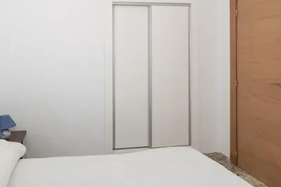 a bedroom with a white bed and a glass door at Hawai Bajo in Faro de Cullera